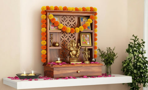 Decorative pooja unit with flowers, candles, and a statue on a white platform.